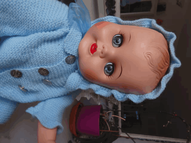 a baby doll wearing a blue sweater with buttons