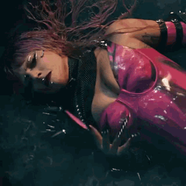 a woman with purple hair is laying on the floor holding a sparkler .