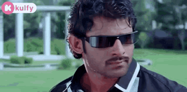 a man wearing sunglasses and a black shirt is looking at the camera .