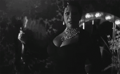 a woman in a black dress is holding a glass of wine .