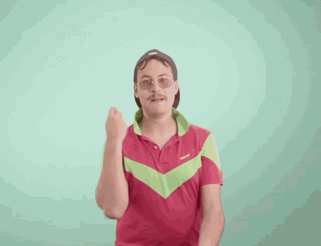 a man wearing a hat and sunglasses is clapping his hands against a green background .