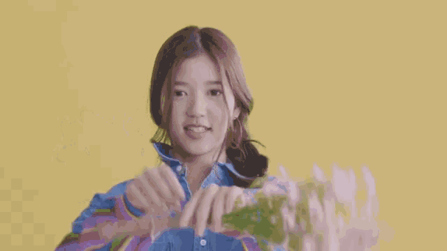 a woman in a blue shirt holds a bouquet of flowers