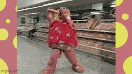 a pink frog mascot is dancing in a supermarket