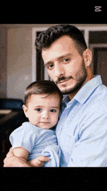 a man in a blue shirt is holding a baby boy in his arms