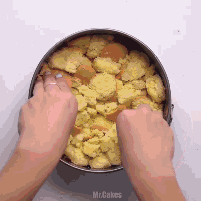 a person 's hands are reaching into a pan of crumbs with the words mr.cakes below them