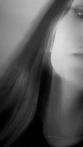 it is a black and white photo of a woman 's face with long hair .