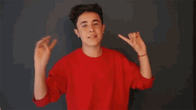 a young man in a red sweater is making a funny face while dancing .
