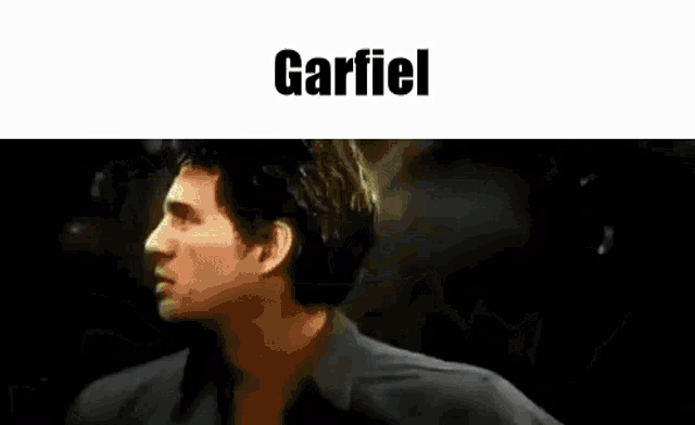 a man in a suit and tie is dancing in a dark room with the word garfiel written above him .