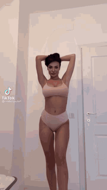 a woman in a pink bikini is standing in front of a white door .