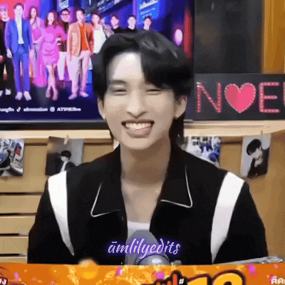 a young man in a black and white jacket is smiling in front of a television .