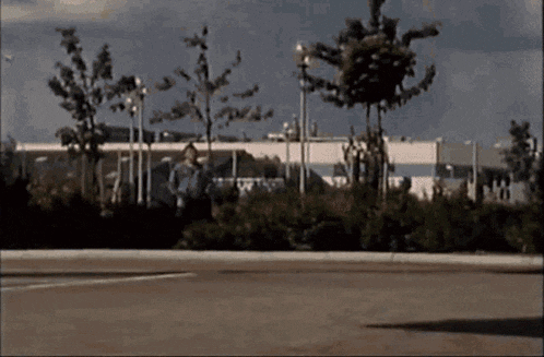 a man is walking down a street with trees in the background