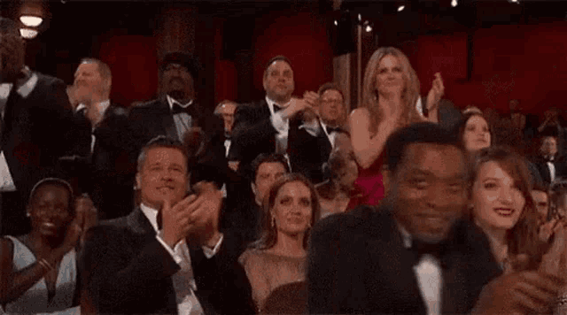a crowd of people are sitting in a theatre applauding .