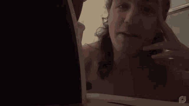 a woman without a shirt is looking at her face in a mirror