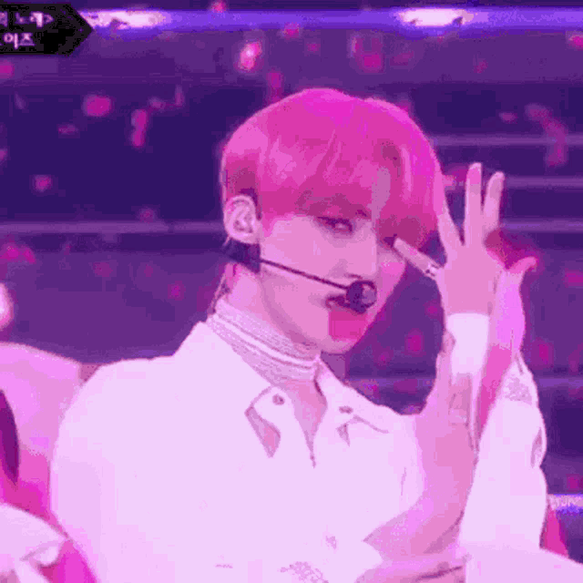 a man with pink hair is wearing a choker and a microphone while performing on stage .