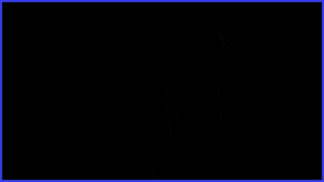a man wearing glasses sits at a desk in front of a blue background