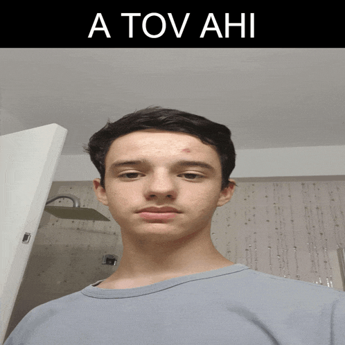 a young man stands in front of a sign that says a tov ahi on it