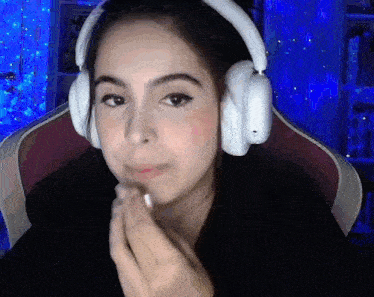a woman wearing headphones is sitting in a chair in front of a blue background .