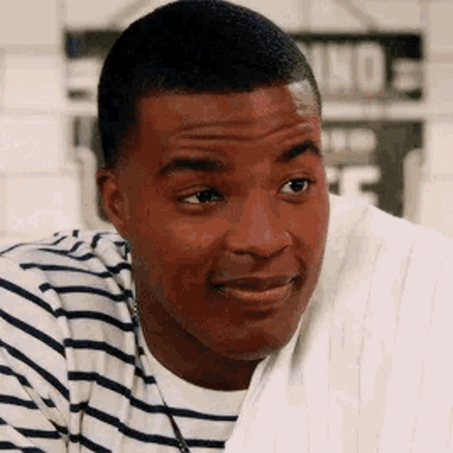 a man in a striped shirt is smiling while holding a towel over his shoulder .