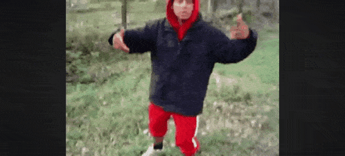a person wearing a black jacket and red shorts is standing in the grass