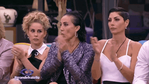 a group of women are sitting in a room with the words grandefratello on the screen