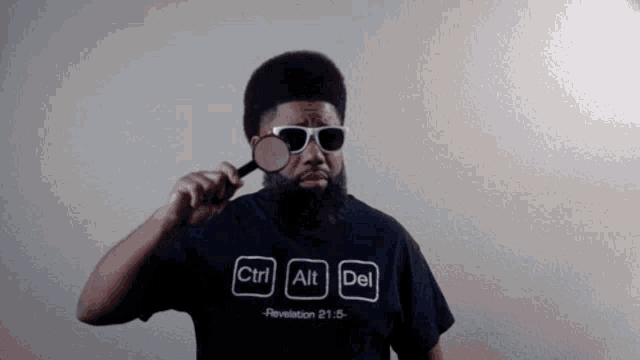 a man wearing sunglasses and a shirt that says ctrl alt del is holding a magnifying glass .
