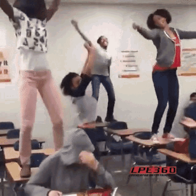 a group of people are jumping in the air in a classroom with the lpe360 logo in the corner