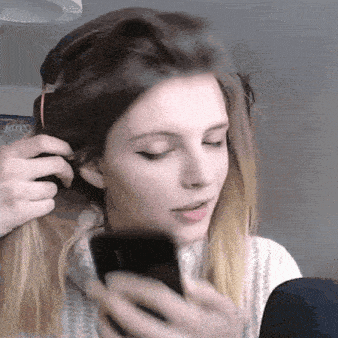 a woman is looking at her phone while getting her hair done
