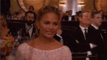 a woman in a pink dress is sitting in a crowd of people at a awards ceremony .