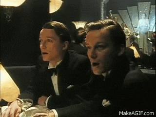 two men in tuxedos are sitting at a table in a room .