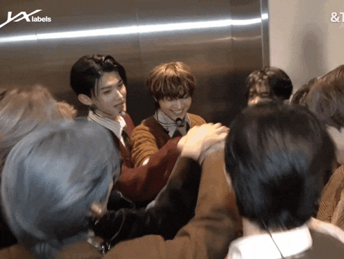 a group of people are huddled together in an elevator with the letters jx labels on the bottom