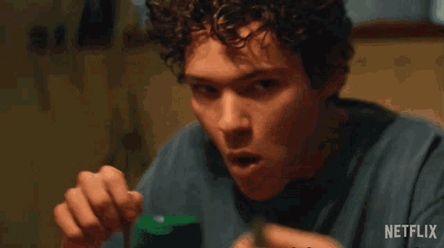 a man with curly hair is sitting at a table with a netflix logo on the bottom