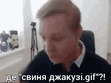 a man is sitting in a chair in front of a window and talking in a video call .