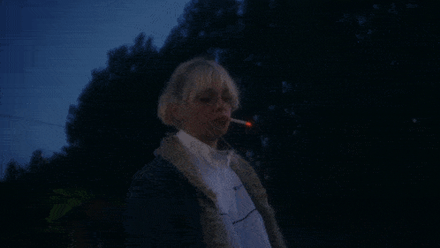 a woman is standing in front of a fire with her eyes closed