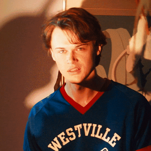 a young man wearing a blue westville jersey looks at the camera