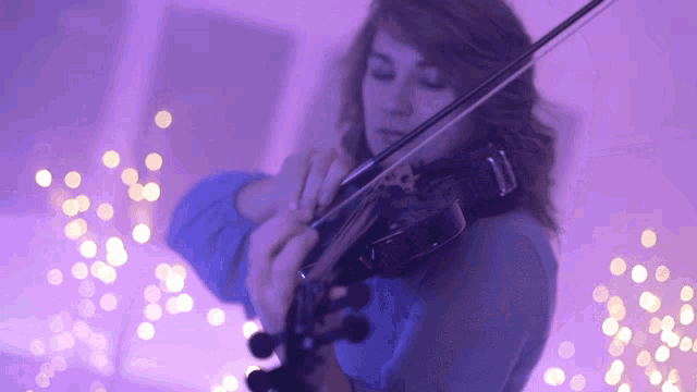 a woman is playing a violin in a purple room