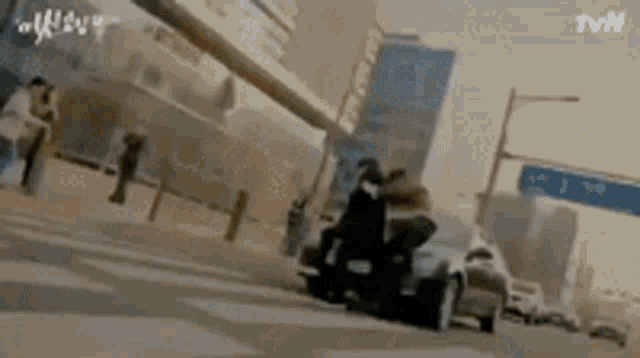a man is riding a scooter down a street next to a car .