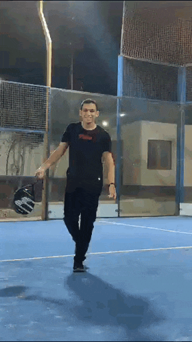 a man is walking on a tennis court holding a paddle .