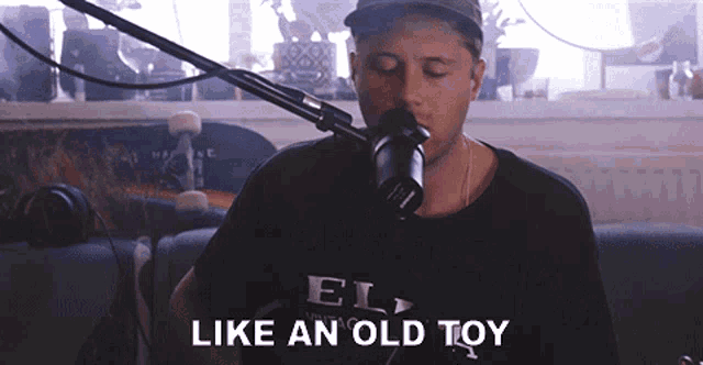 a man singing into a microphone with the words like an old toy on the bottom