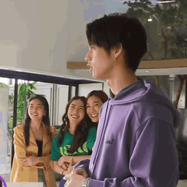 a man in a purple hoodie is standing in front of two women