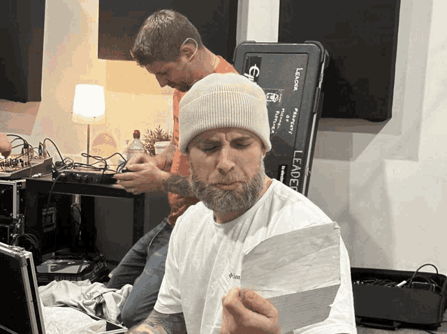 a man wearing a white beanie is holding a piece of paper