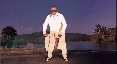 a man in a white coat is dancing in front of a lake .