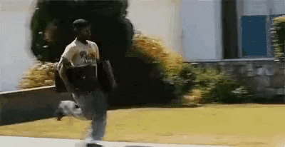 a man is running down a sidewalk while carrying a skateboard .