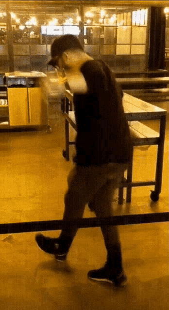 a man in a black shirt and black shoes is walking across a wooden floor