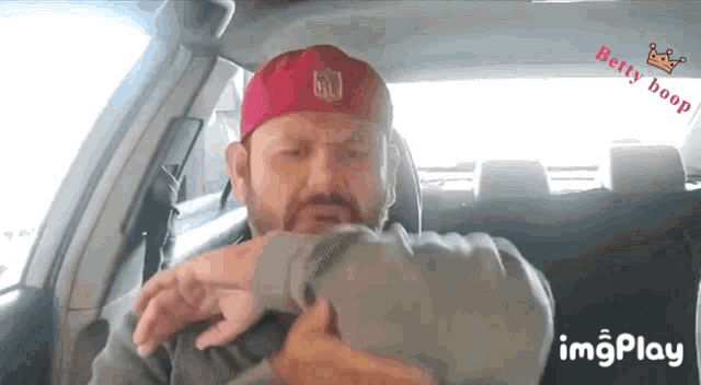 a man in a red hat with the nfl logo on it is sitting in a car
