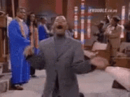 a man in a suit is kneeling down with his arms outstretched in front of a crowd of people .