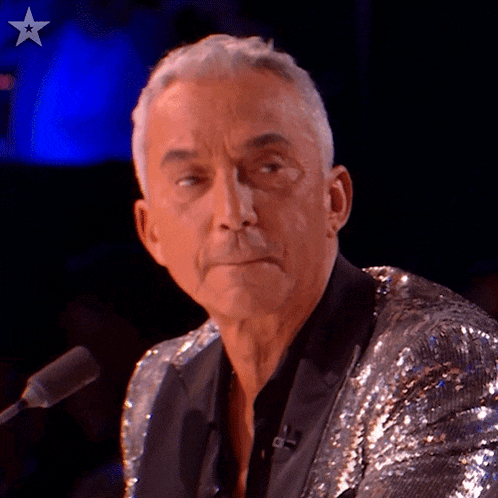 a man in a sequined jacket is sitting at a microphone