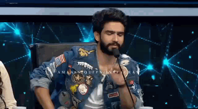 a man with a beard is sitting in a chair with a microphone in front of him .