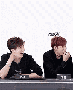 two men are sitting at a table with a sign that says omg !
