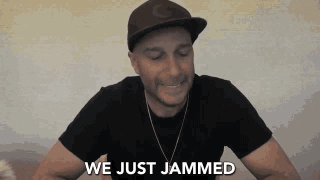 a man wearing a hat and a black shirt is smiling and saying we just jammed