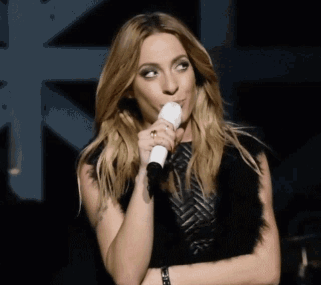 a woman is singing into a microphone and making a funny face